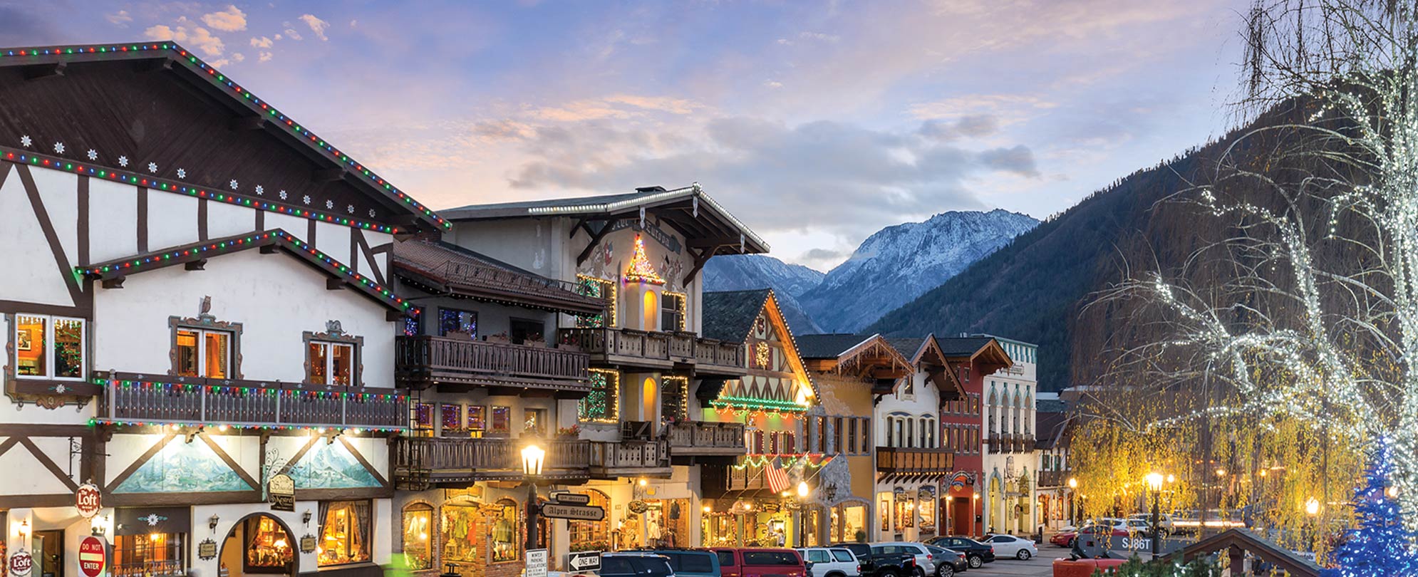 A city street with decorated Bavarian buildings and mountains in the background in Leavenworth, Washington